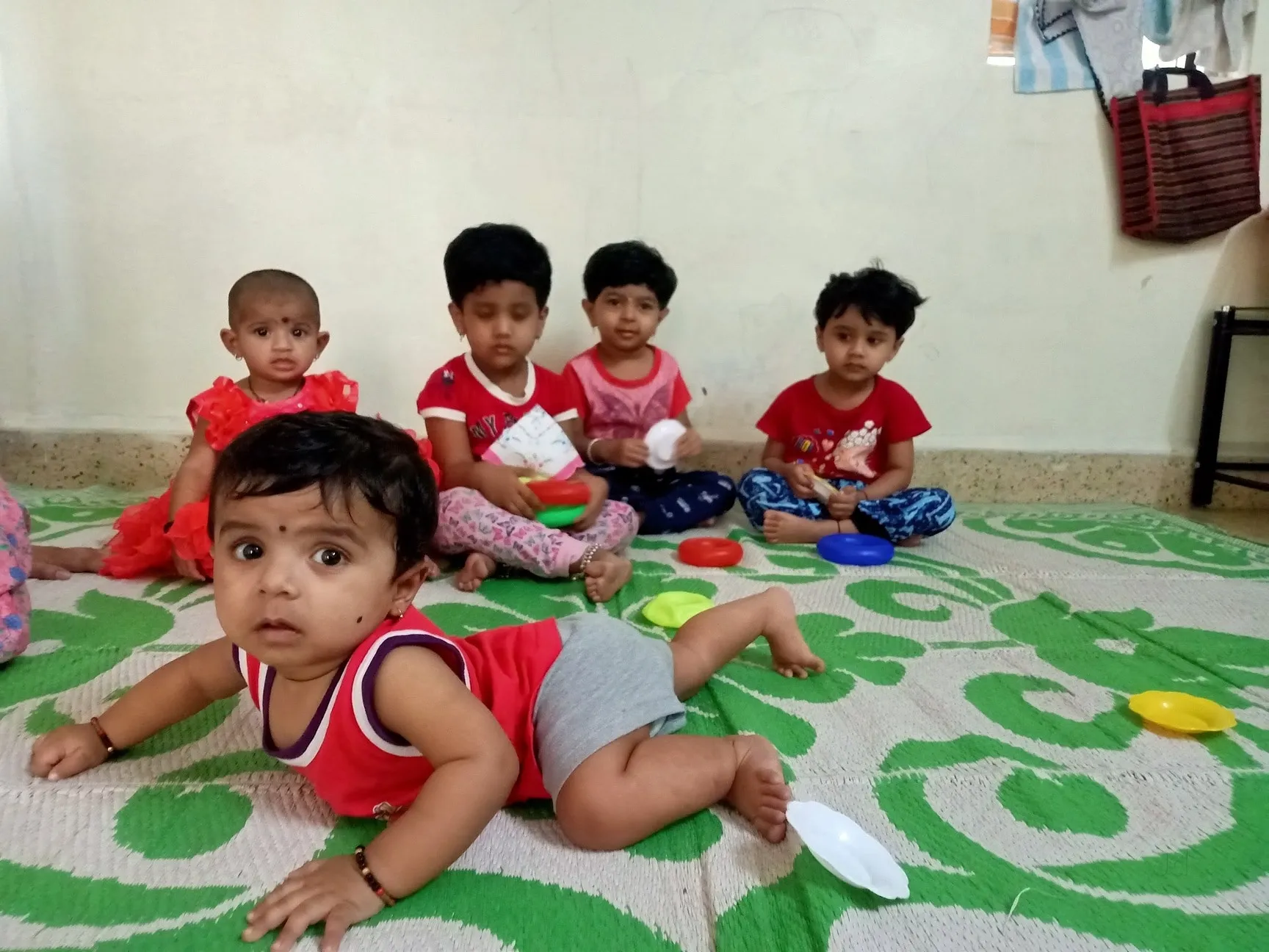 Babies and toddlers playing safely together on a soft green mat at Maza Ghar