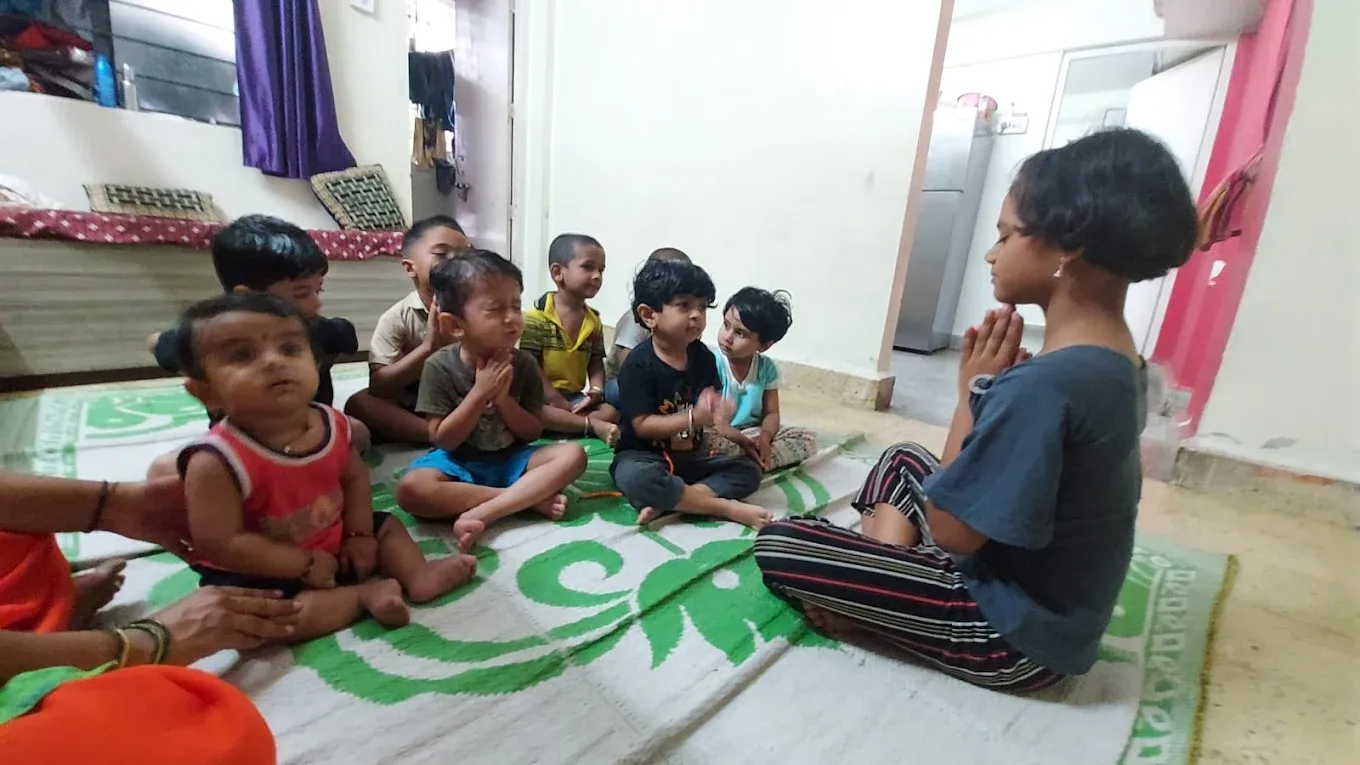 Children sitting with folded hands during prayer and shlok time at Maza Ghar