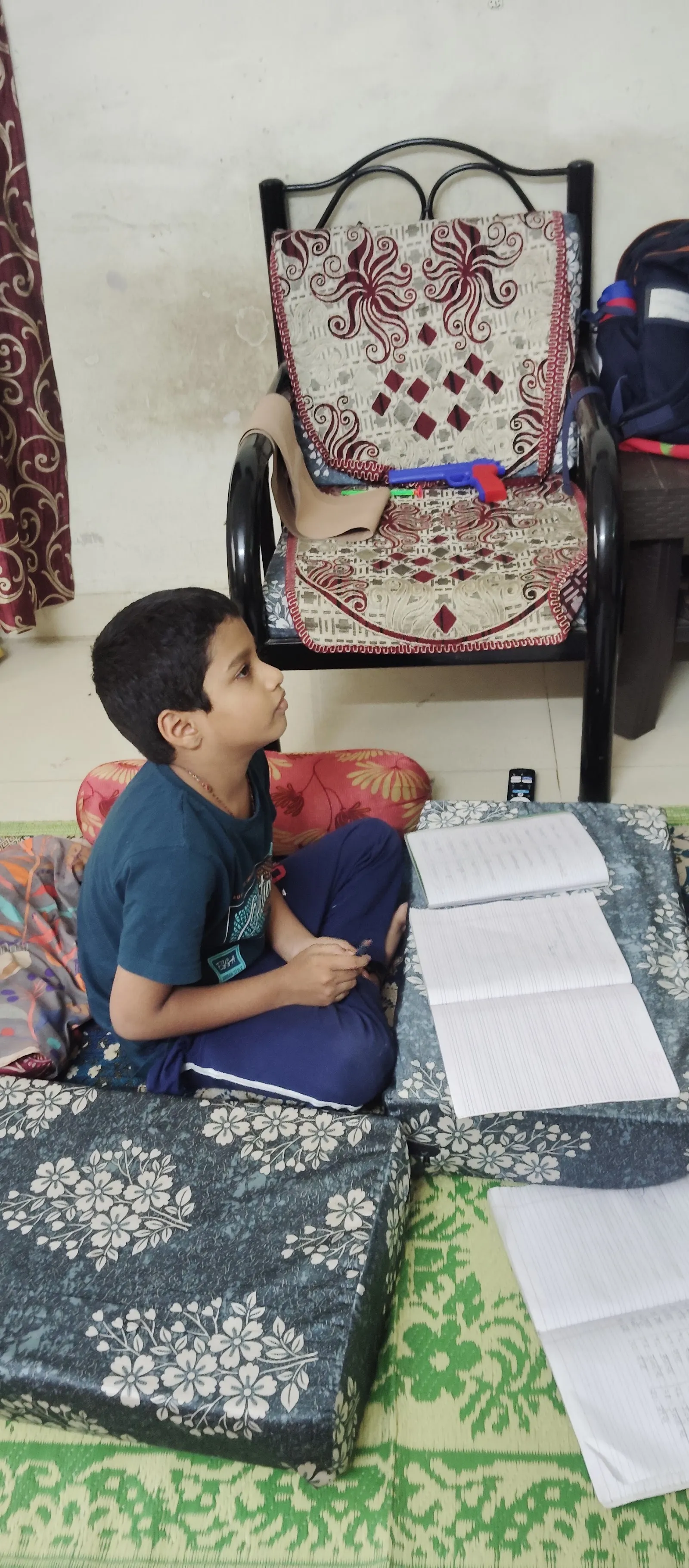 A school-age boy doing his homework at a low desk at Maza Ghar
