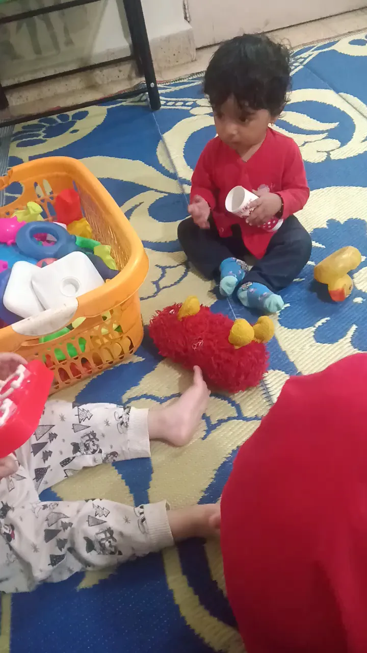 A toddler playing with a basket of toys on a soft mat at Maza Ghar